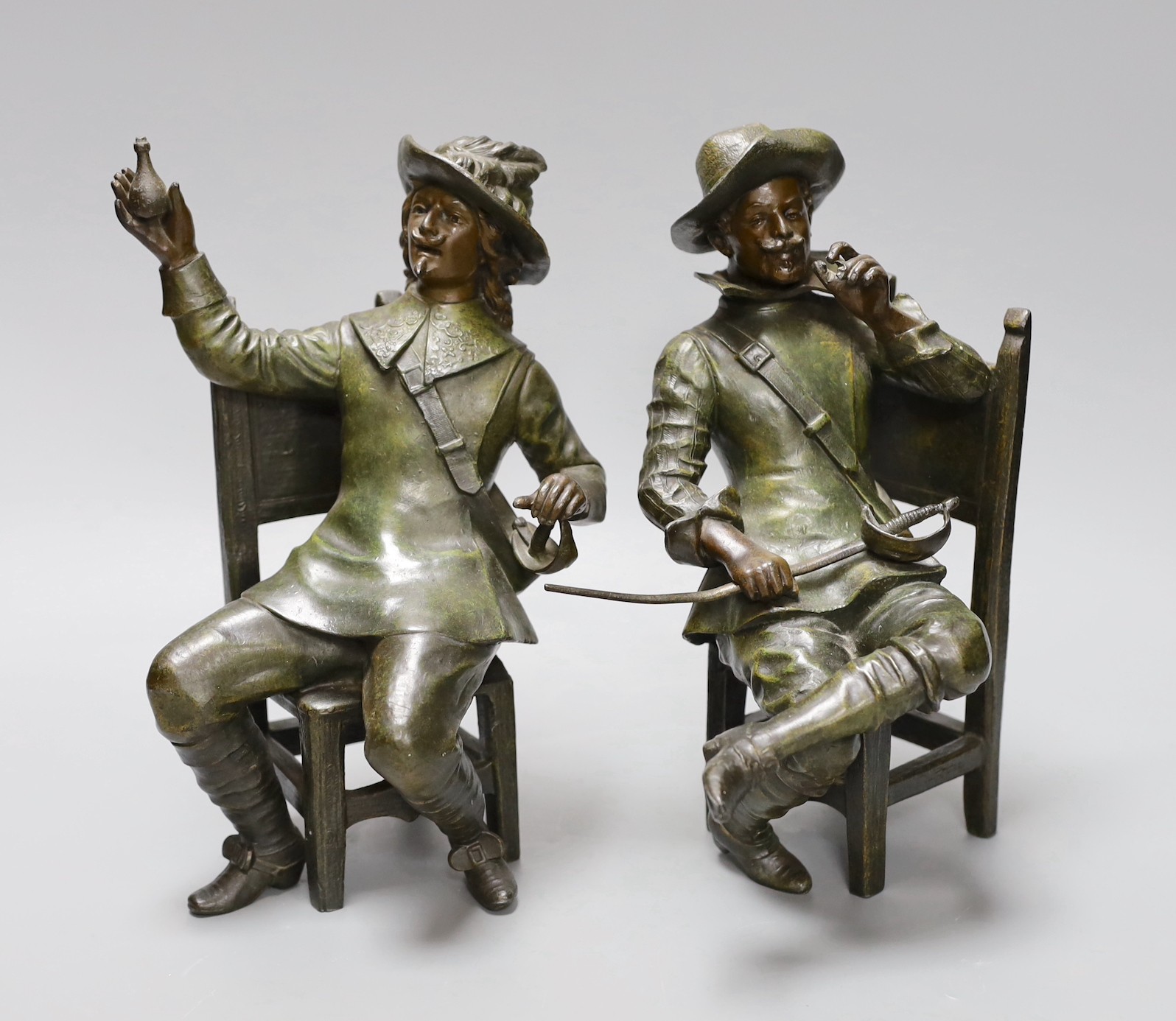 A pair of early 20th century patinated bronzed metal figures of seated cavaliers, 25 cms high